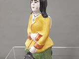 une figurine représentant une femme assise sur une étagère en verre