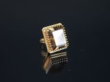 un gros plan d'une bague en or sertie d'une pierre blanche