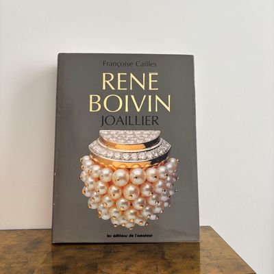 the book is sitting on a table next to a pair of pearls