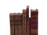 several old books are stacked on top of each other on a white surface