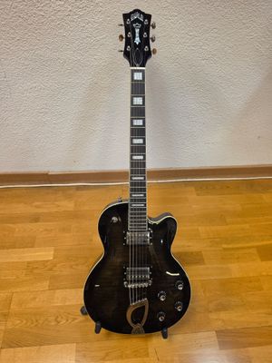 a black electric guitar sitting on top of a hard wood floor