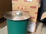 une poubelle verte posée par terre à côté d'un carton