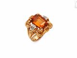 un gros plan d'une bague sertie d'une pierre orange et de diamants