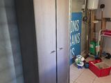 une photo d'une pièce avec un réfrigérateur et une poubelle