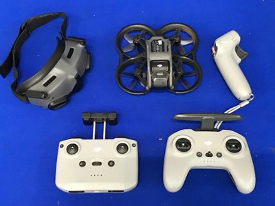 deux télécommandes et une manette posées sur une surface bleue