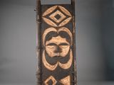 un gros plan sur une plaque en bois sur laquelle est représenté un visage