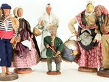 five figurines of people dressed in different costumes
