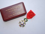 une petite boîte rouge contenant une médaille et un ruban rouge