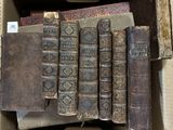 Plusieurs vieux livres se trouvent dans une boîte en carton posée sur une table