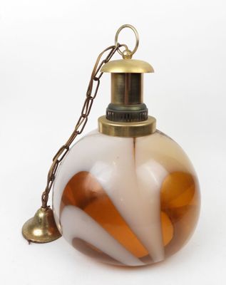 brown and white glass ornament with a brass bell on a chain