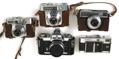 several old cameras are lined up on a white surface