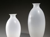 two white vases sitting next to each other on a table