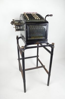 une vieille machine à écrire posée sur un support, sur fond blanc