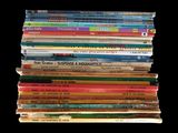 a lot of children ' s books stacked on top of each other