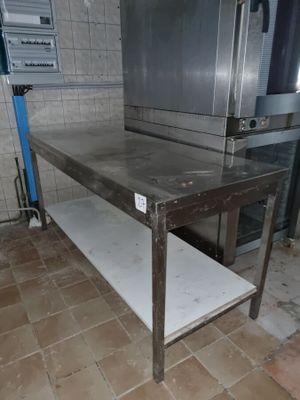 une table en acier inoxydable sur laquelle est posé un micro-ondes, dans une cuisine