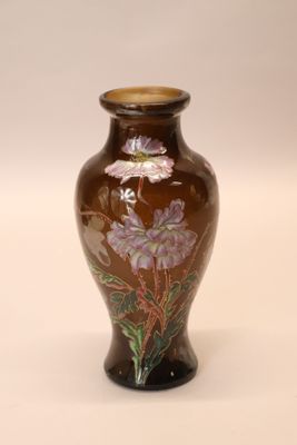 a brown vase with purple flowers on it on a white surface