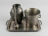 un plateau en argent sur lequel se trouvent un vase en argent et une coupe en argent