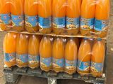 Des bouteilles de jus d'orange sont empilées sur une palette devant un camion