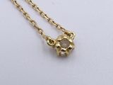 a gold necklace with a flower charm on a chain
