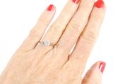 a woman ' s hand with a red manicure holding a diamond ring