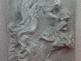 une image représentant une sculpture du visage d'un homme sur une surface rouge