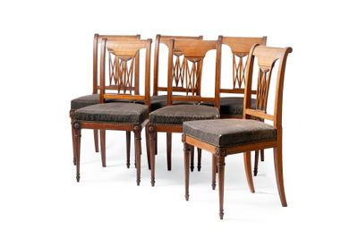 quatre chaises en bois à l'assise rembourrée sont alignées devant un fond blanc