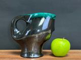 a green apple sitting next to a black coffee cup