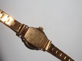 a close up of a gold watch on a white surface