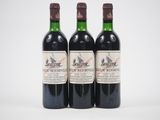 trois bouteilles de vin rouge posées l'une à côté de l'autre sur une surface blanche