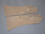 two pairs of beige leather gloves on a blue surface