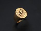 a gold signet ring with the letter e on it