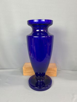 un vase bleu posé sur un socle en bois