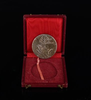 une vieille médaille d'argent dans une boîte rouge sur fond noir