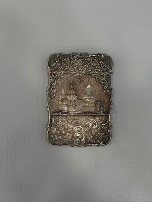 an antique silver cigarette case with a picture of a castle on it