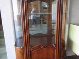 a wooden cabinet with a glass door in the corner of the room