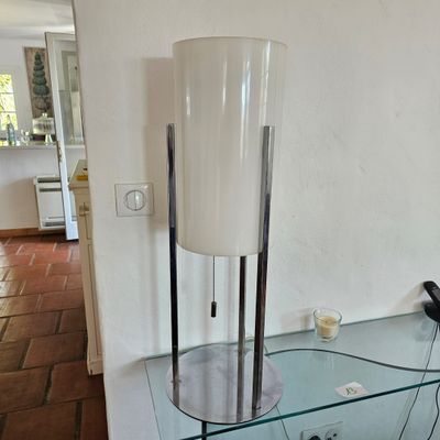 une table en verre sur laquelle se trouvent une lampe et un téléphone