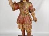 an old wooden statue of a man in a red outfit