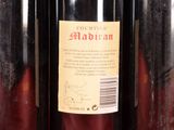three bottles of red wine are lined up on a shelf