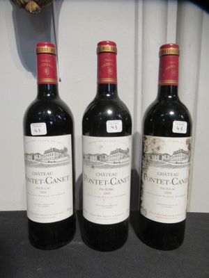 trois bouteilles de vin posées sur une table, à côté d'une horloge