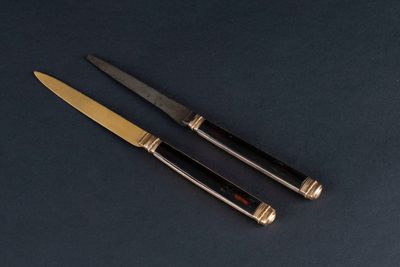 deux couteaux posés sur une table, sur fond noir