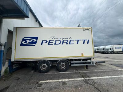 un grand camion blanc garé devant un immeuble