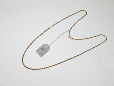 une chaîne en or à laquelle est accrochée une médaille, posée sur une surface blanche