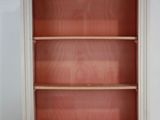 une vieille bibliothèque avec un cadre blanc et une étagère rouge