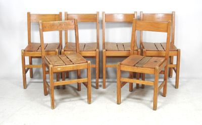four wooden chairs are lined up against a white wall