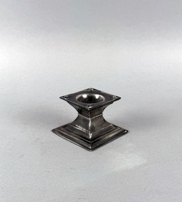 a silver candle holder on a white surface with a white background