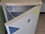 un petit réfrigérateur blanc dans le coin d'une pièce