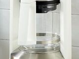 a white coffee maker sitting on a counter next to a cup