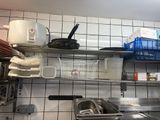 a metal shelf with pots and pans on it in a kitchen