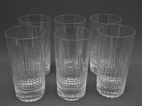 quatre verres transparents sont alignés sur une surface grise