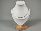 mannequin blanc avec une chaîne en or, posé sur un socle en bois